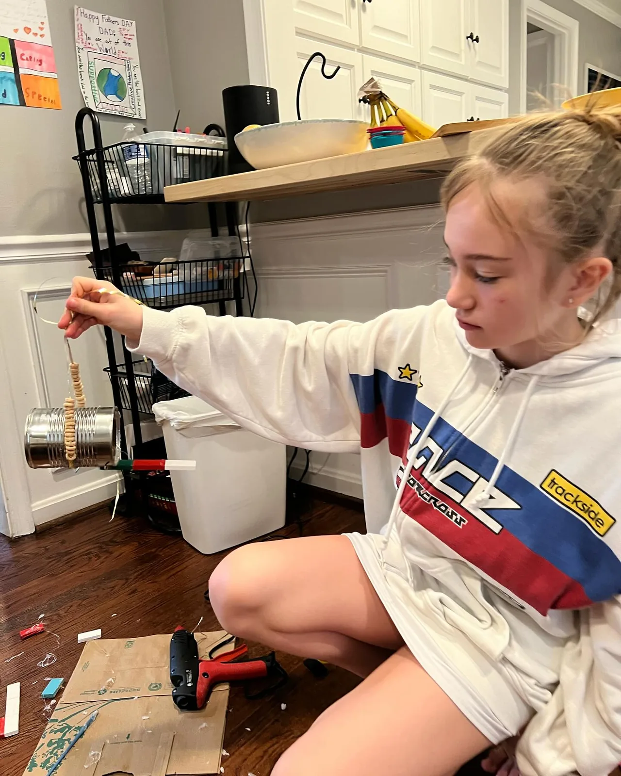 A girl assembles a hanging bird feeder.