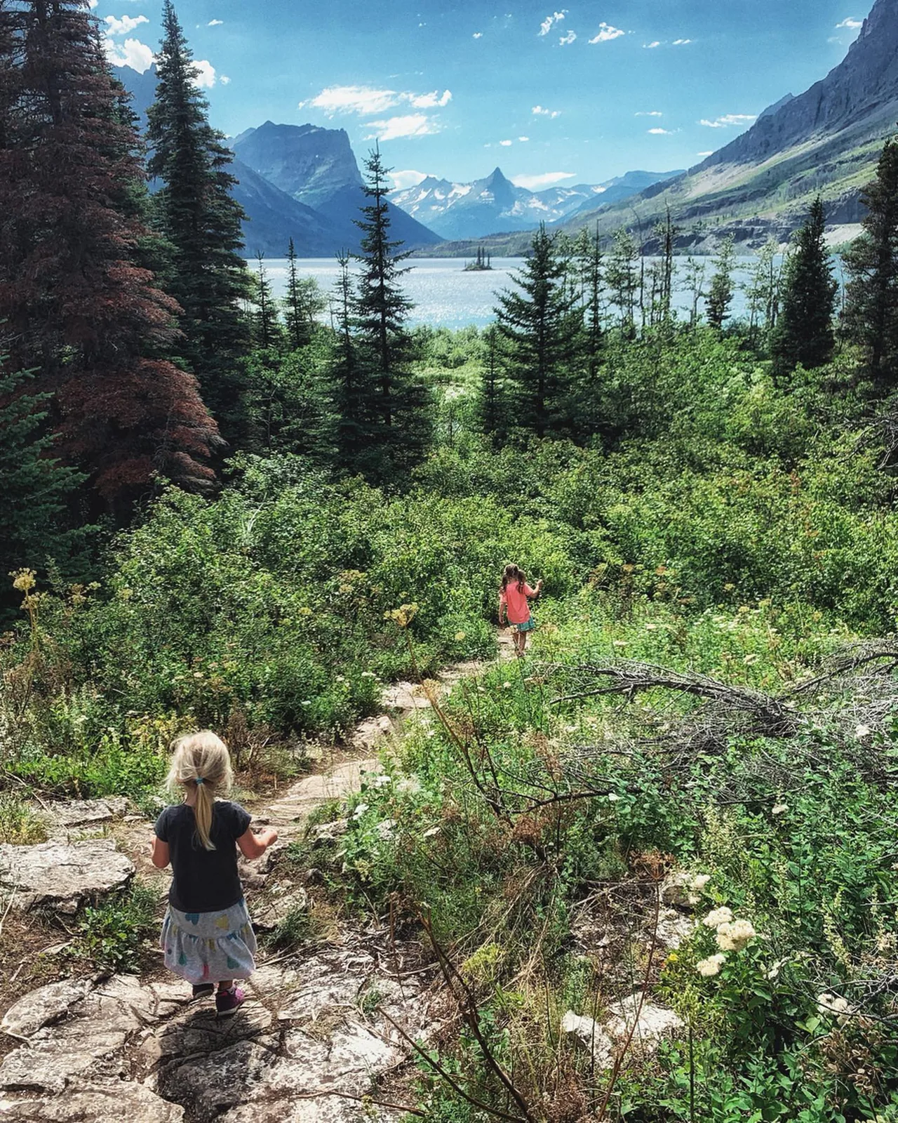 Children follow a trail through a mountain valley.
