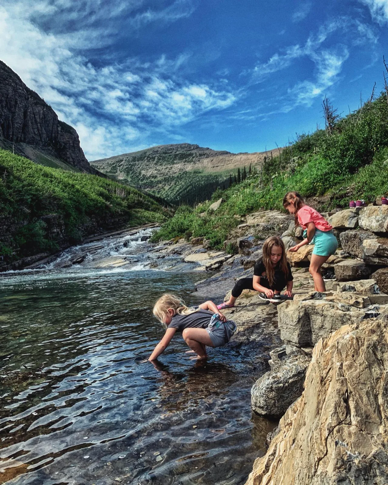 Children play beside a clear mountain stream.