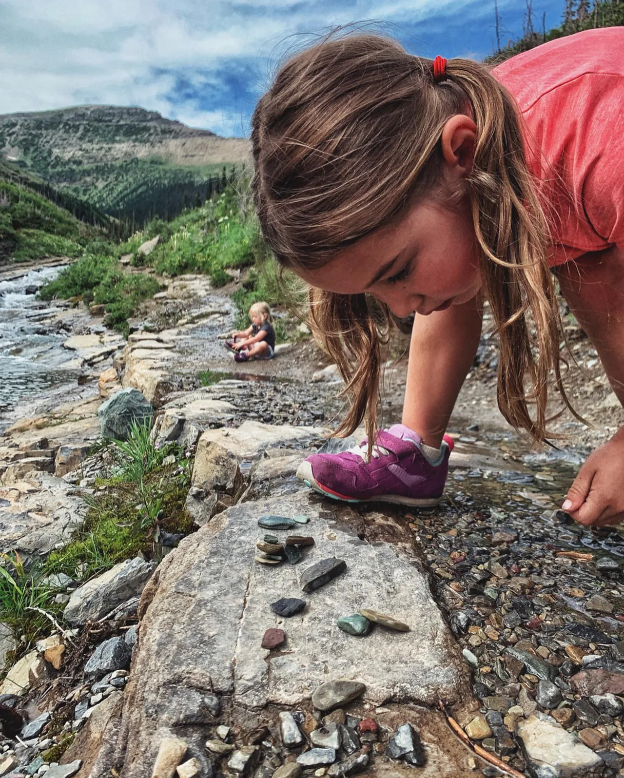 A child examines colorful stones by the water.