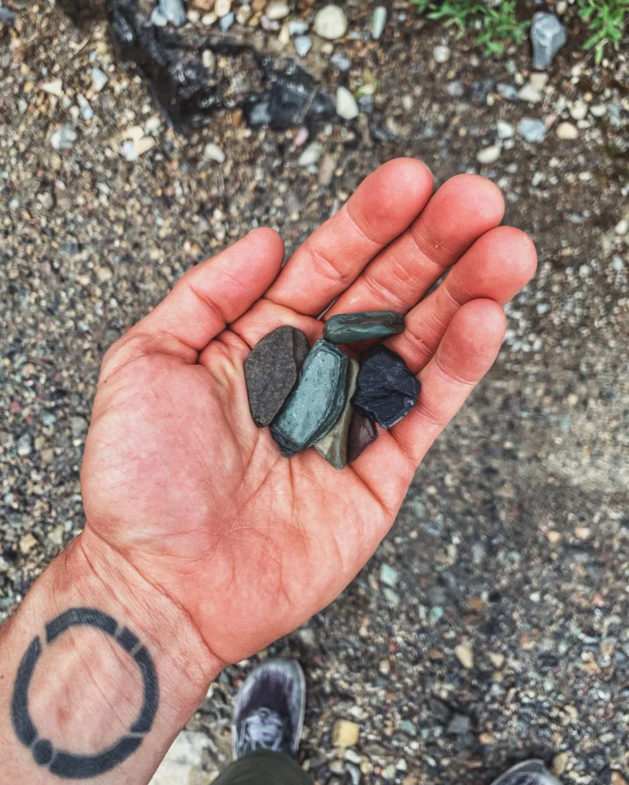 A hand holds smooth stones collected by the lake.