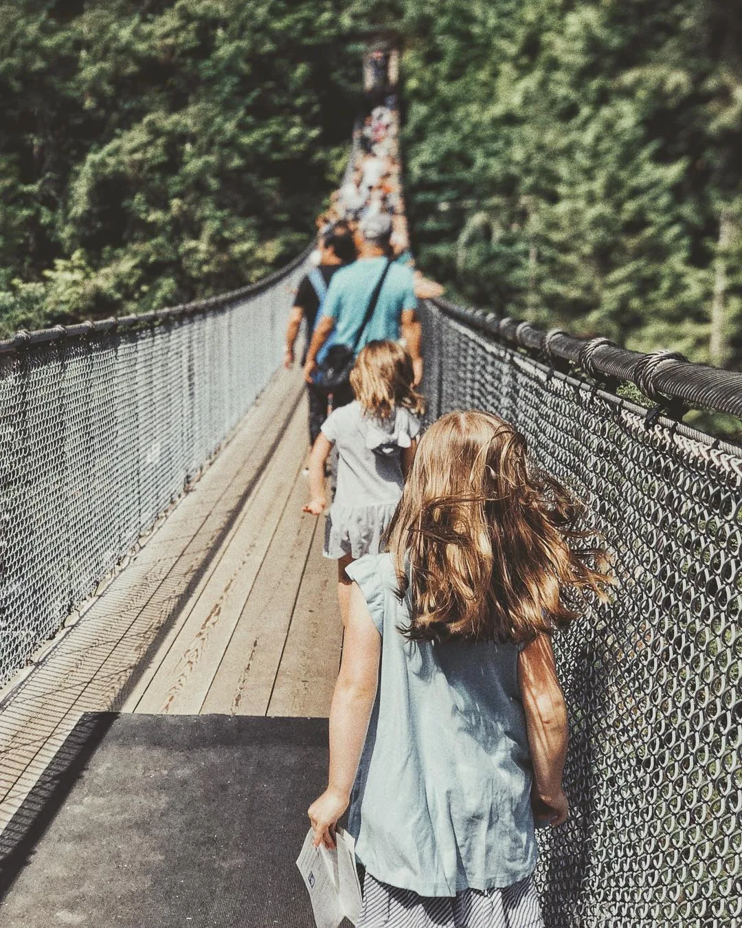 The girls walk ahead across a suspension bridge.