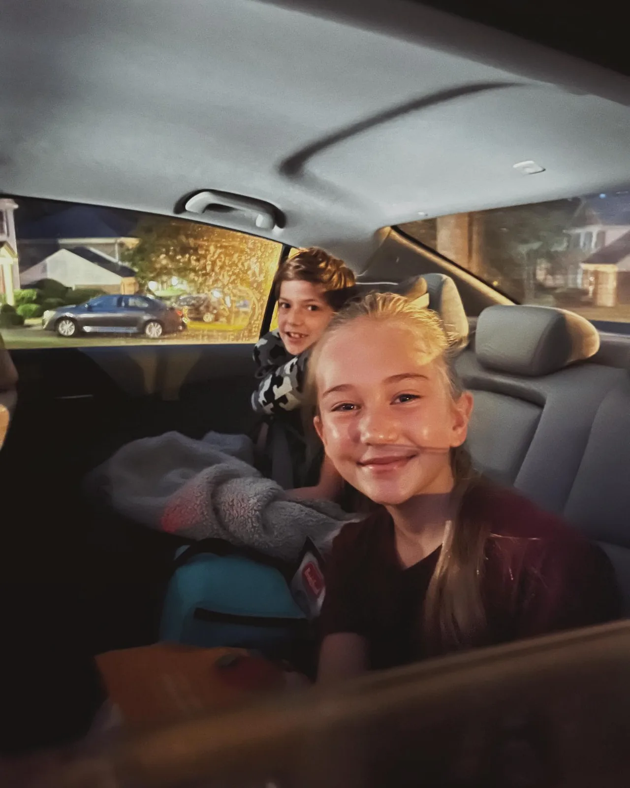 Emerson smiles from the back seat of a car.