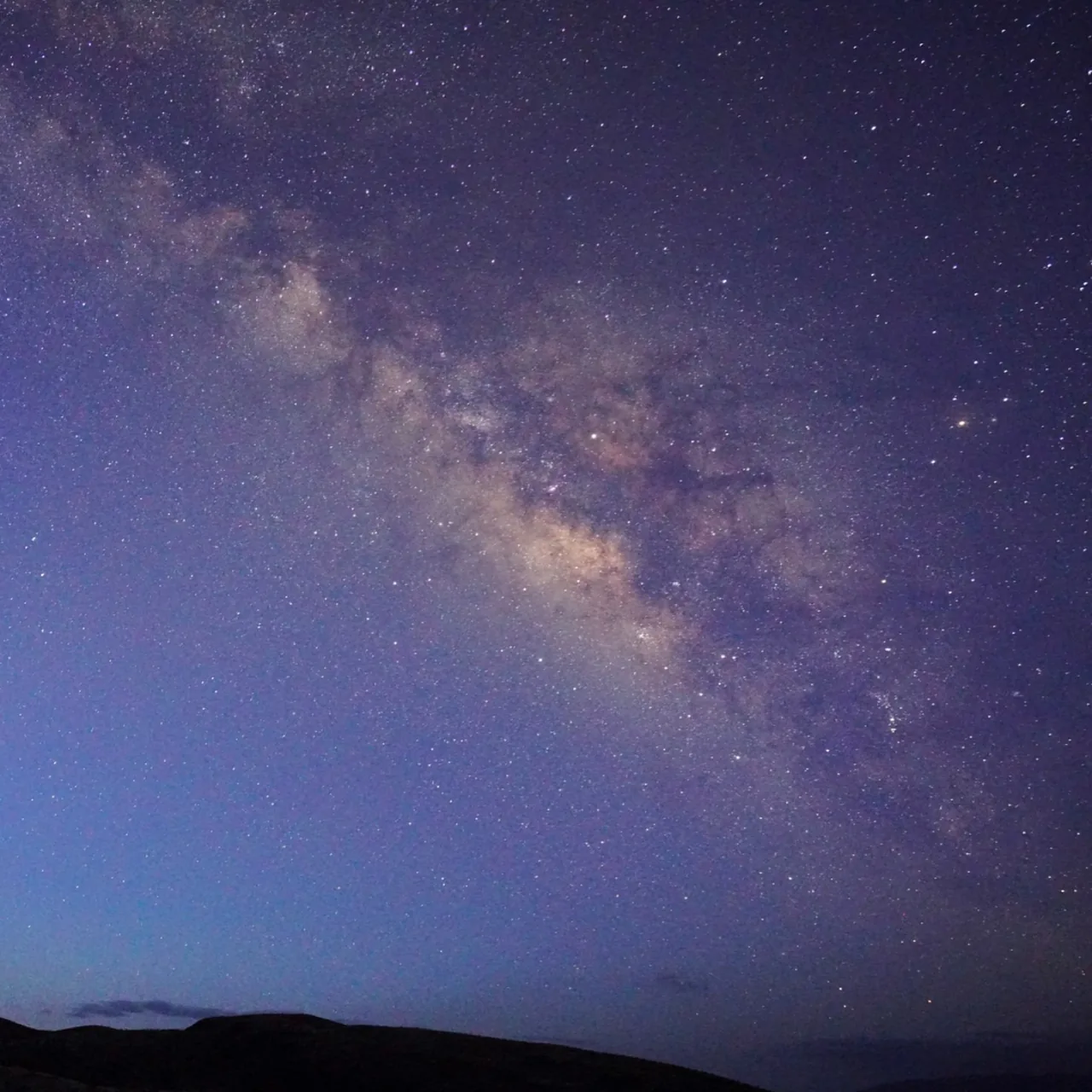 The Milky Way stretches across a purple night sky.