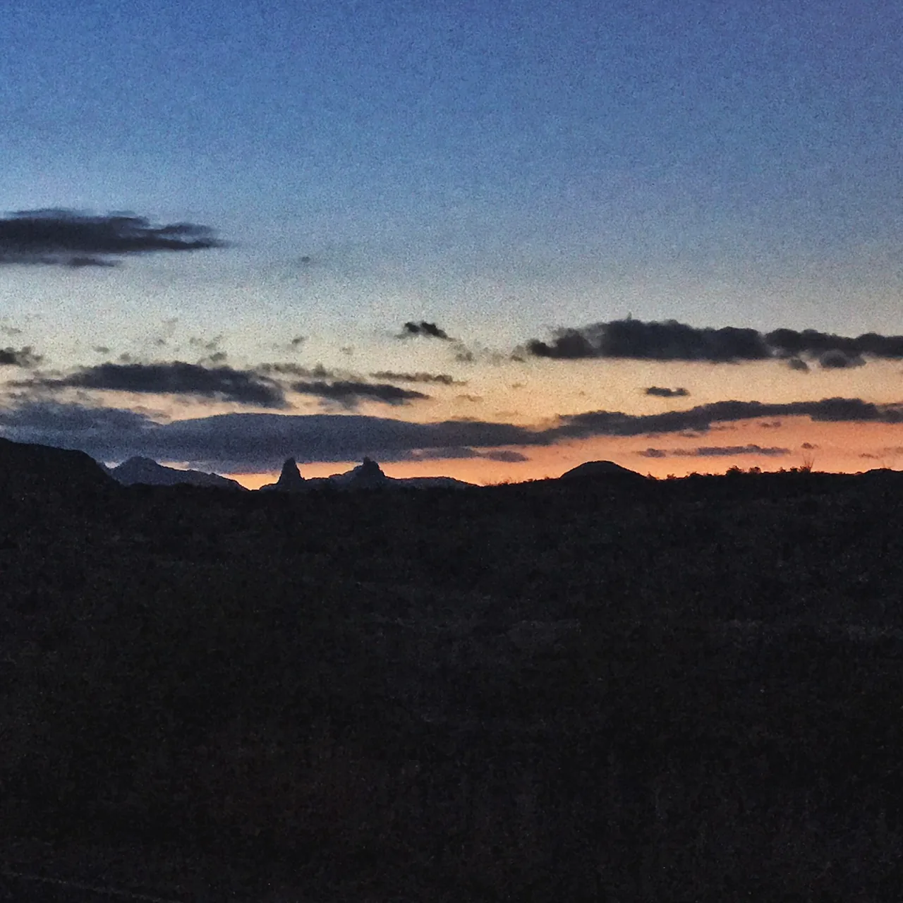An orange sunrise illuminates the horizon beyond dark hills.